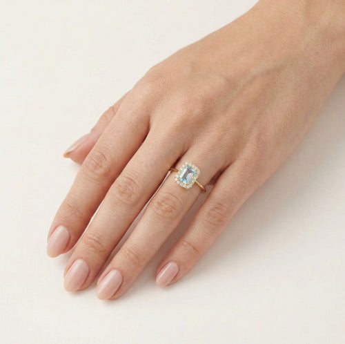 Halo-Ring aus Gold mit blauem Topas im Smaragdschliff