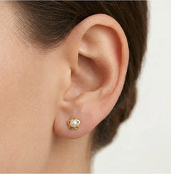 Gold earrings with an engraved flower outline and a white round pearl
