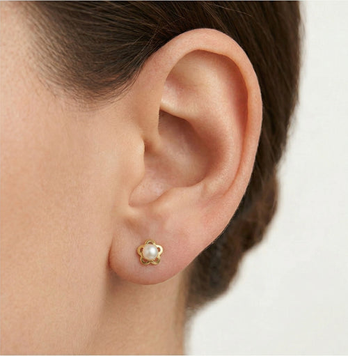 Gold earrings with an engraved flower outline and a white round pearl