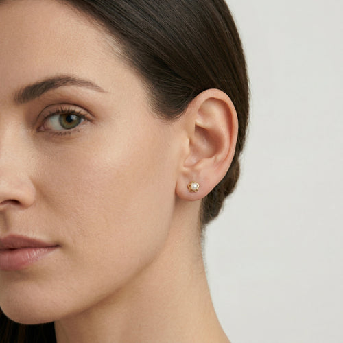 Gold earrings with an engraved flower outline and a white round pearl